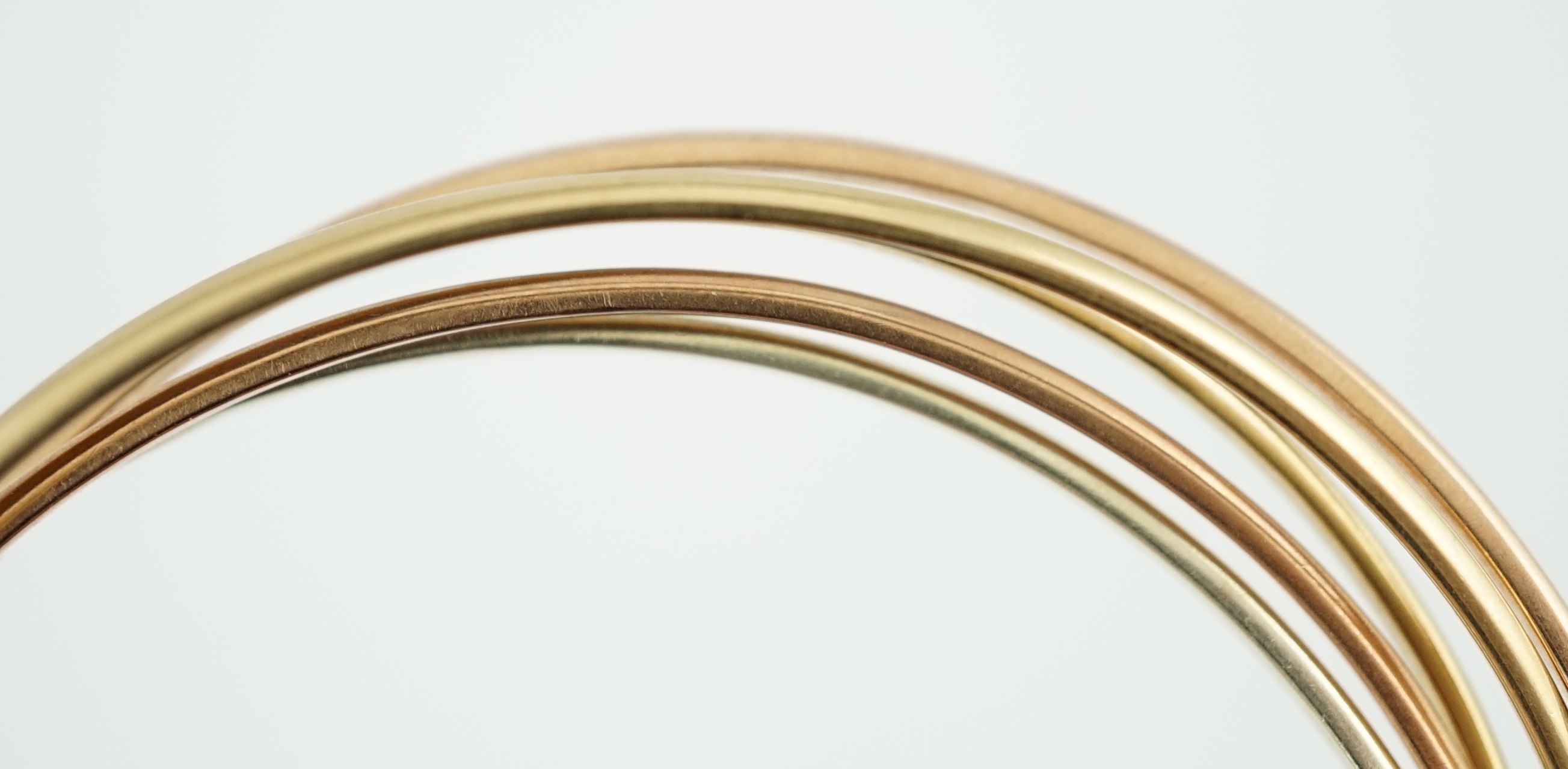 A set of five modern three colour 9ct gold inter-looping bangles